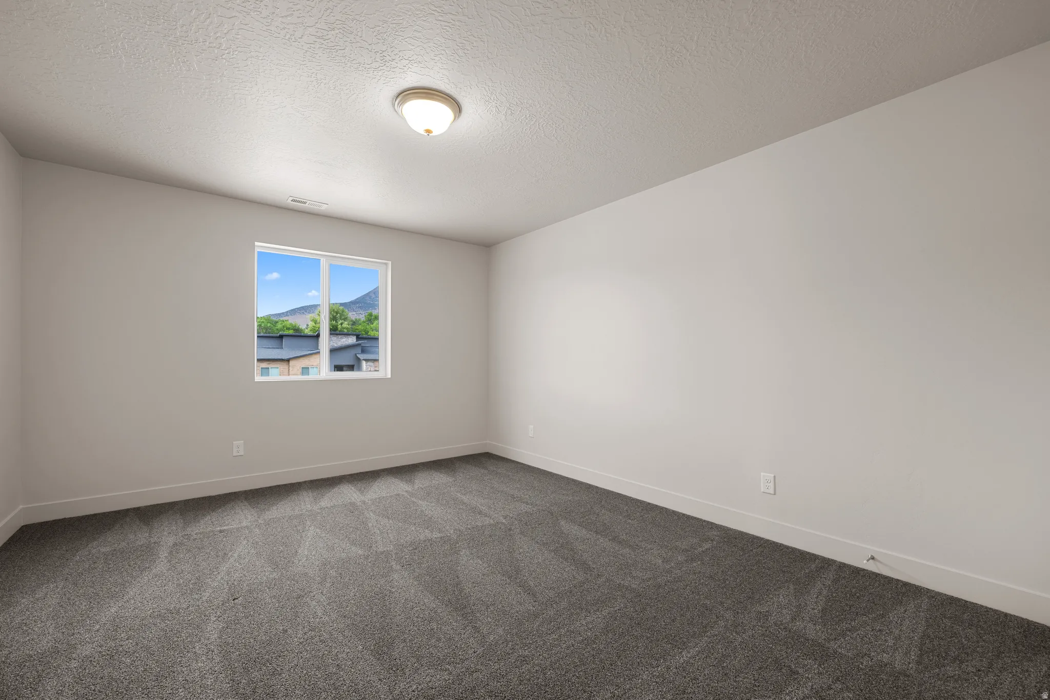 Spare room with dark carpet and a textured ceiling