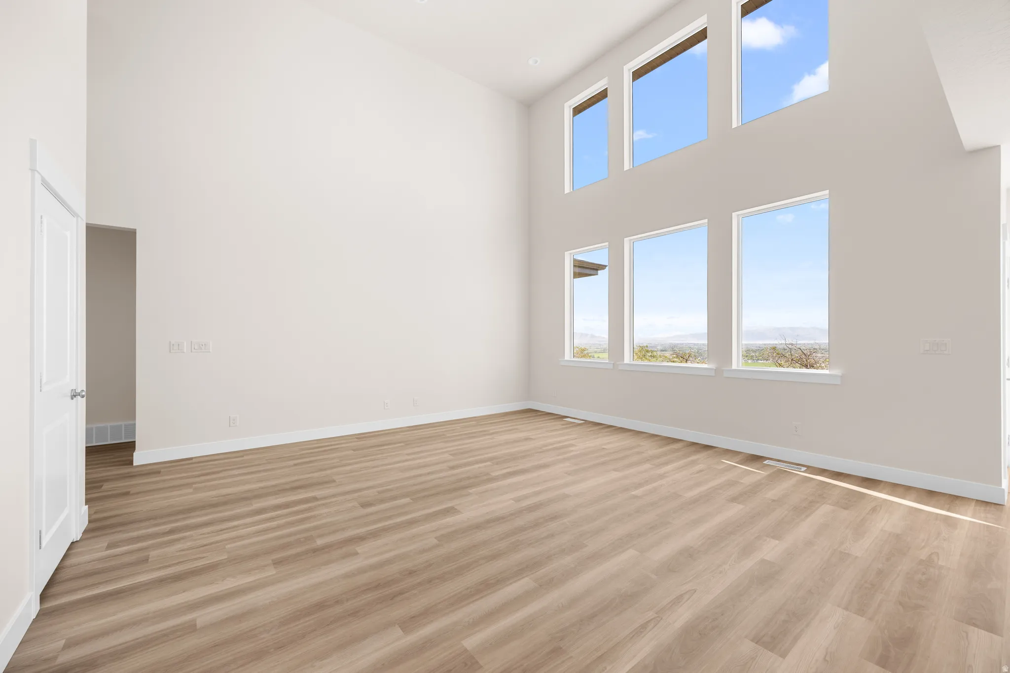 Spacious room with a vaulted ceiling, wood-finish flooring, and multiple large windows