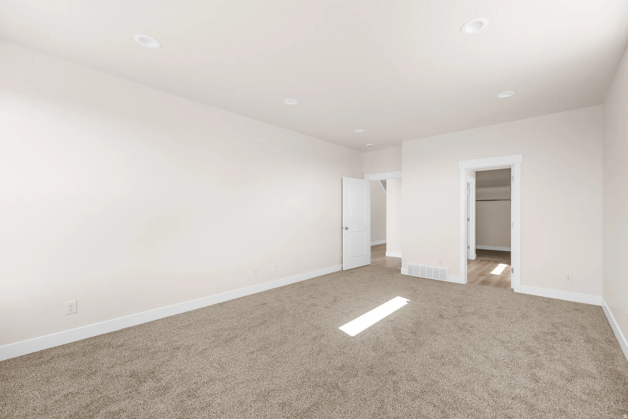 Spacious room with plush carpeting, recessed lighting, white trim, and light-toned walls