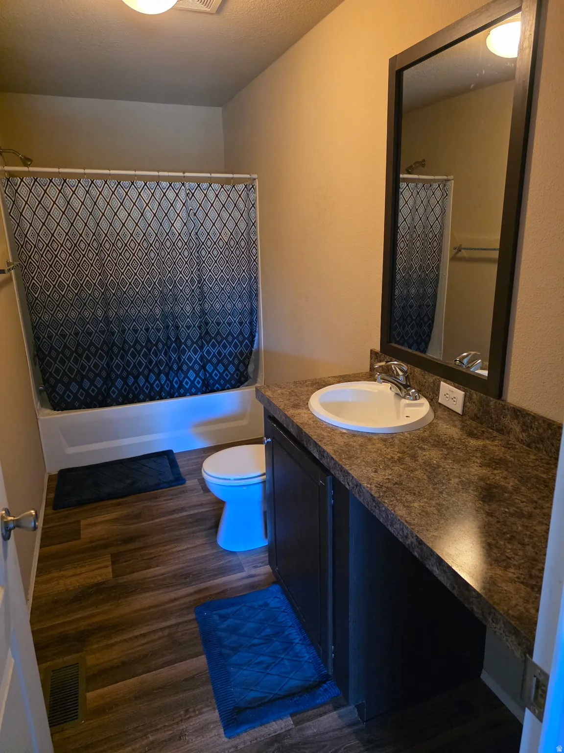Bathroom with vanity, dark wood finished floors, and shower / tub combo