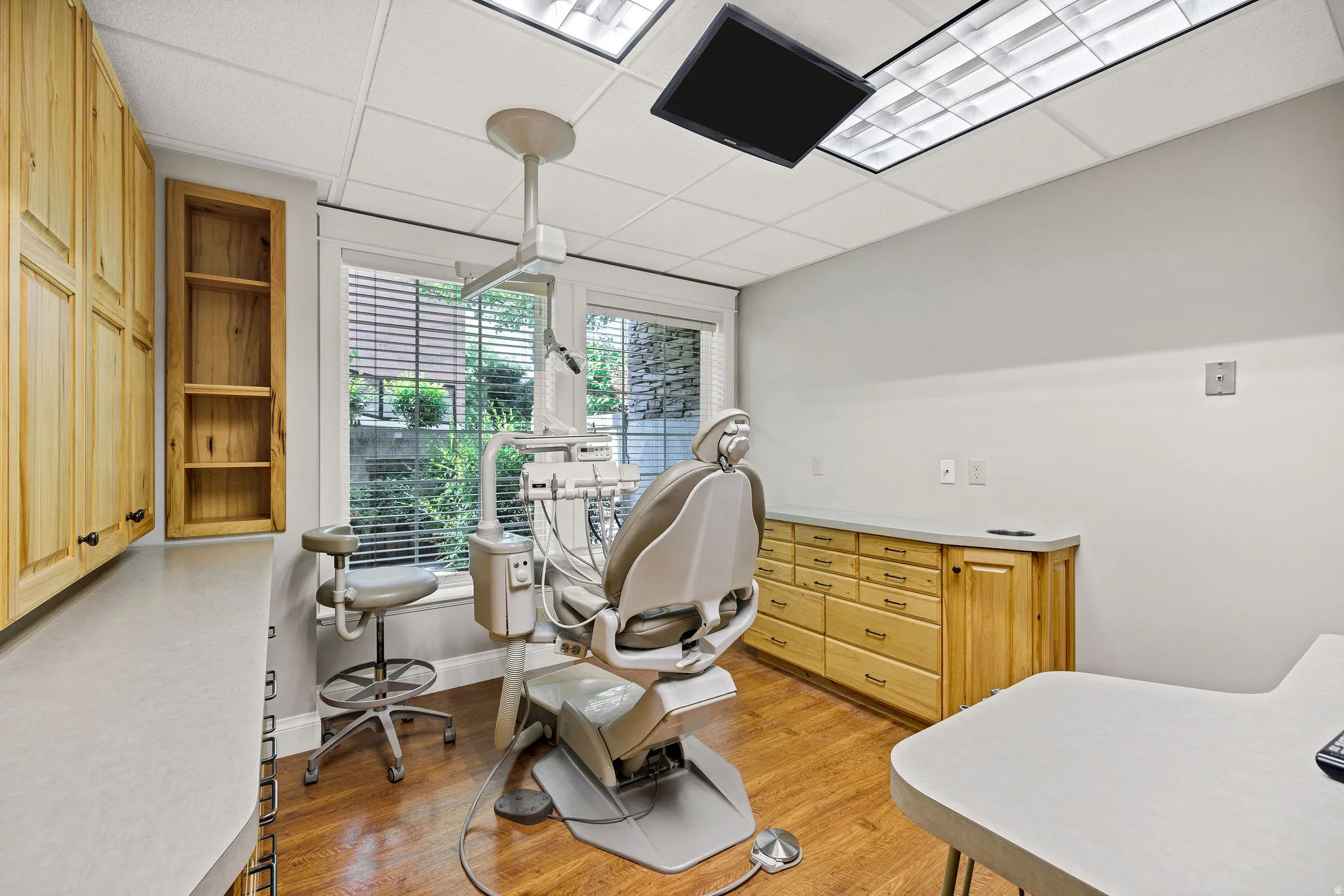 Procedure room with a paneled ceiling and light wood-type flooring and oal cabinetry