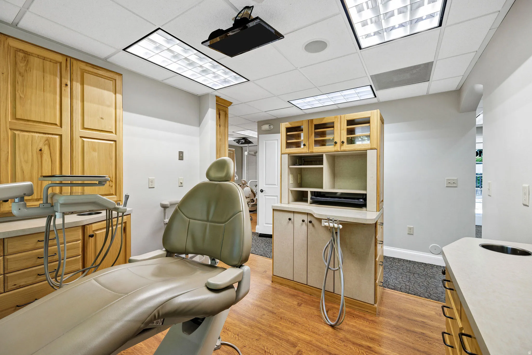 Procedure room with light wood-style floors and a drop ceiling and oak cabinetry