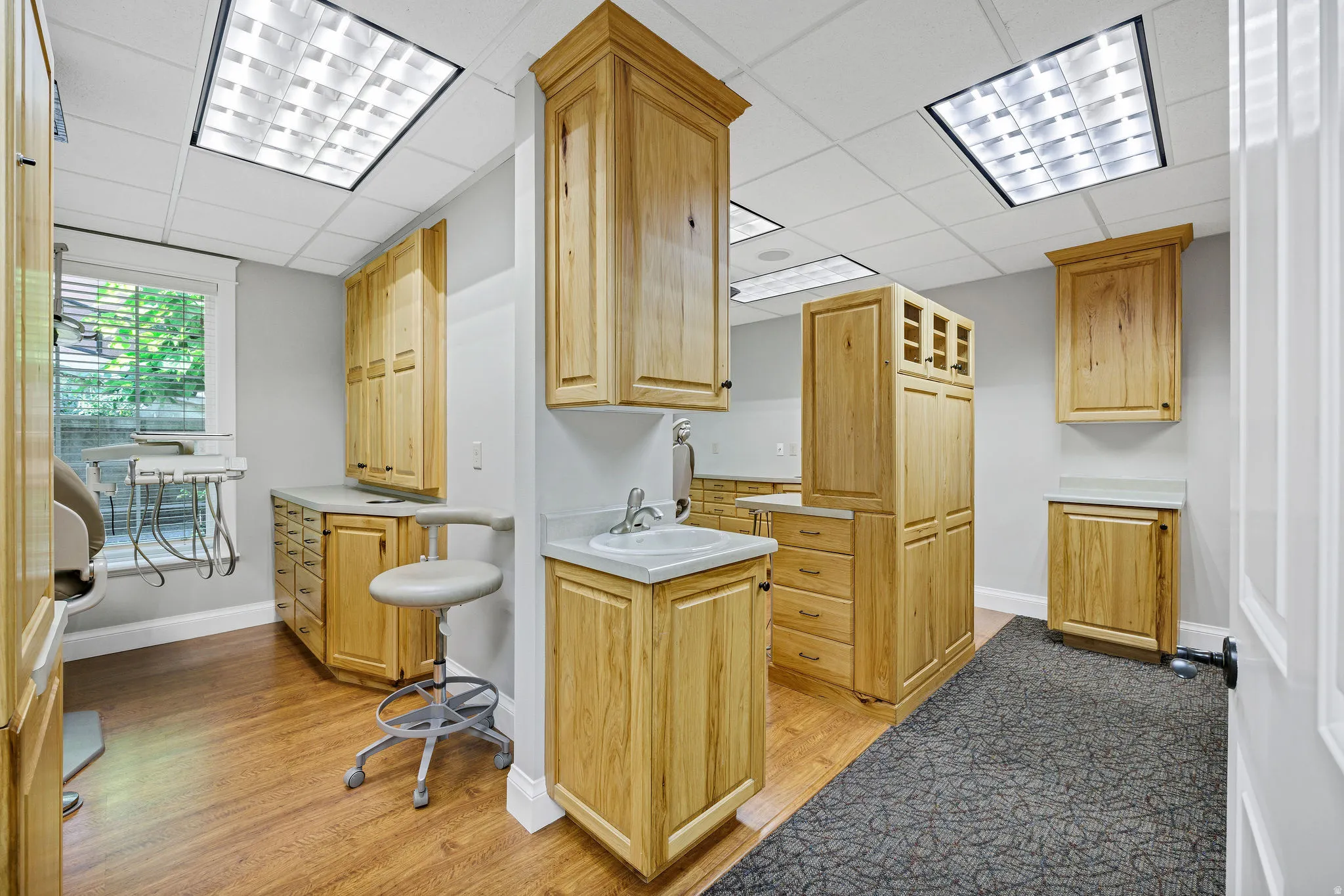 Procedure room featuring light countertops, light wood-style floors, a drop ceiling, and oak cabinets