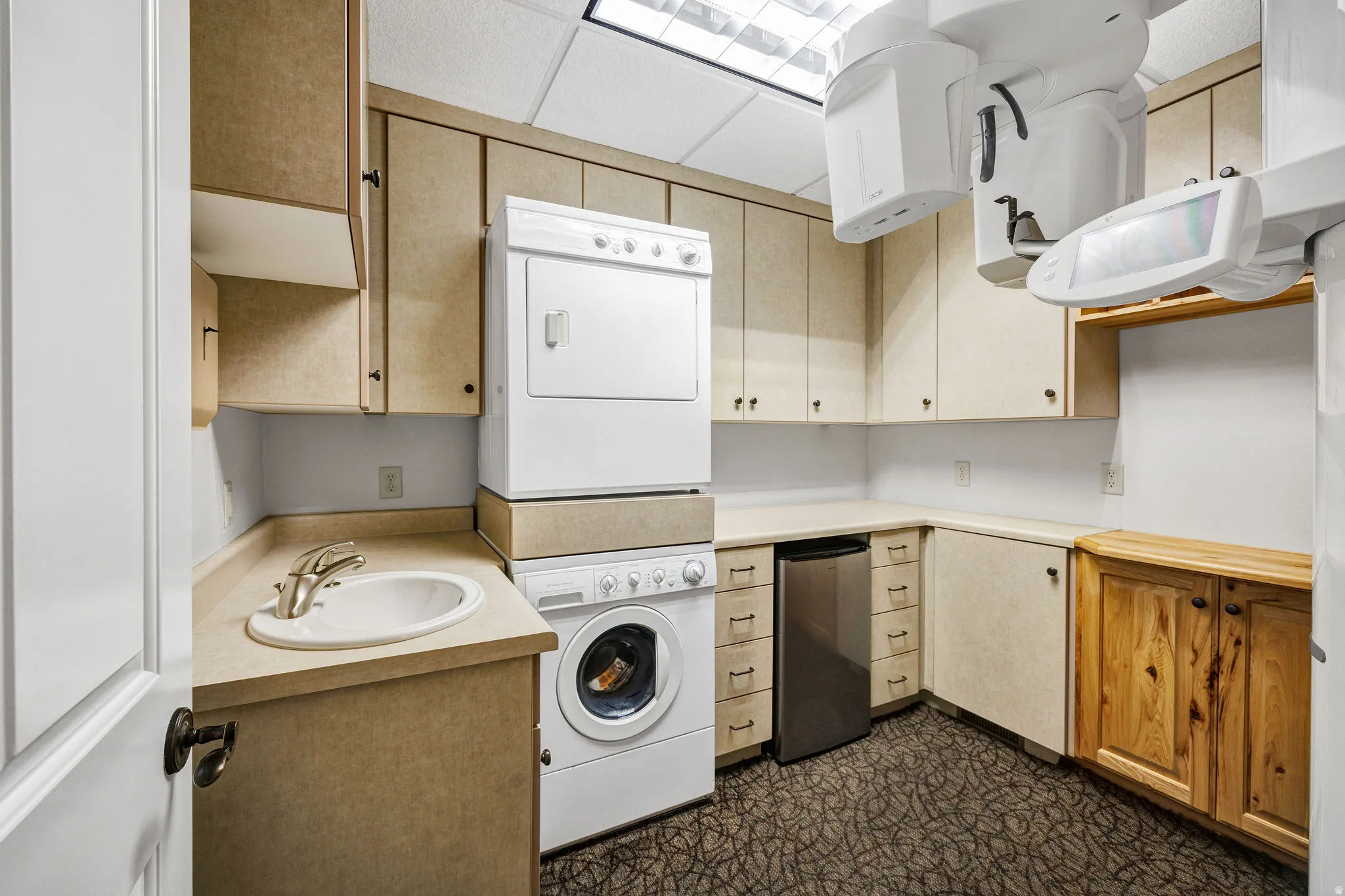 Laundry room or break room with stacked washing machine and dryer and cabinet space