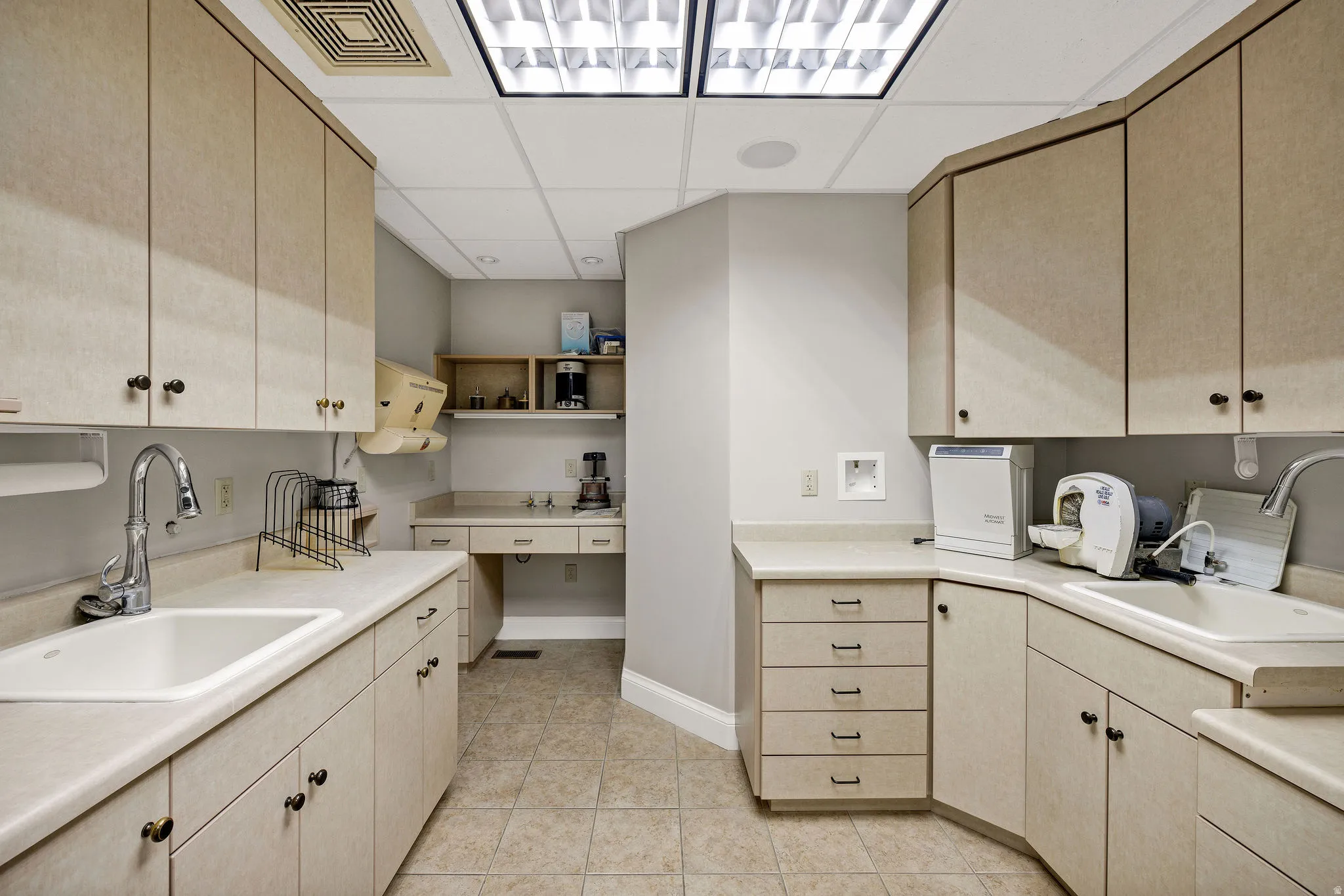 Lab room featuring a drop ceiling, light wood finish cabinets, light countertops, light tile patterned floors, and open shelves