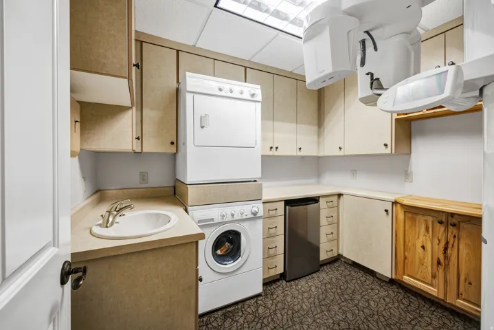 Laundry room or break room with stacked washing machine and dryer and cabinet space