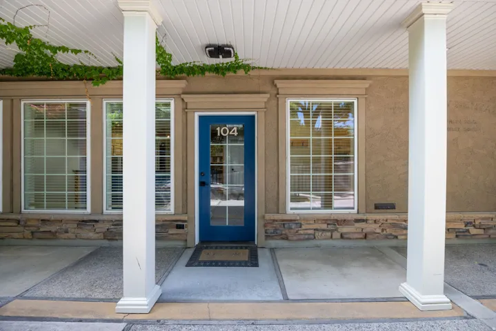 Doorway to property featuring a porch, stone siding, and stucco siding