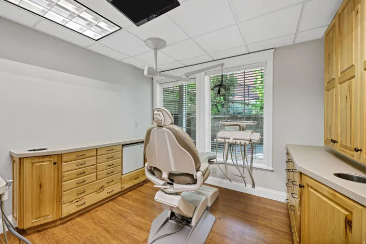 Procedure room featuring a drop ceiling and light wood-type flooring with oak cabinetry.