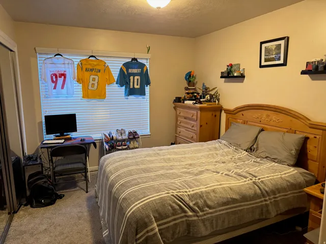 Bedroom with carpet flooring, an office area, and a textured ceiling