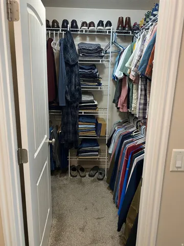 Walk in closet featuring light colored carpet