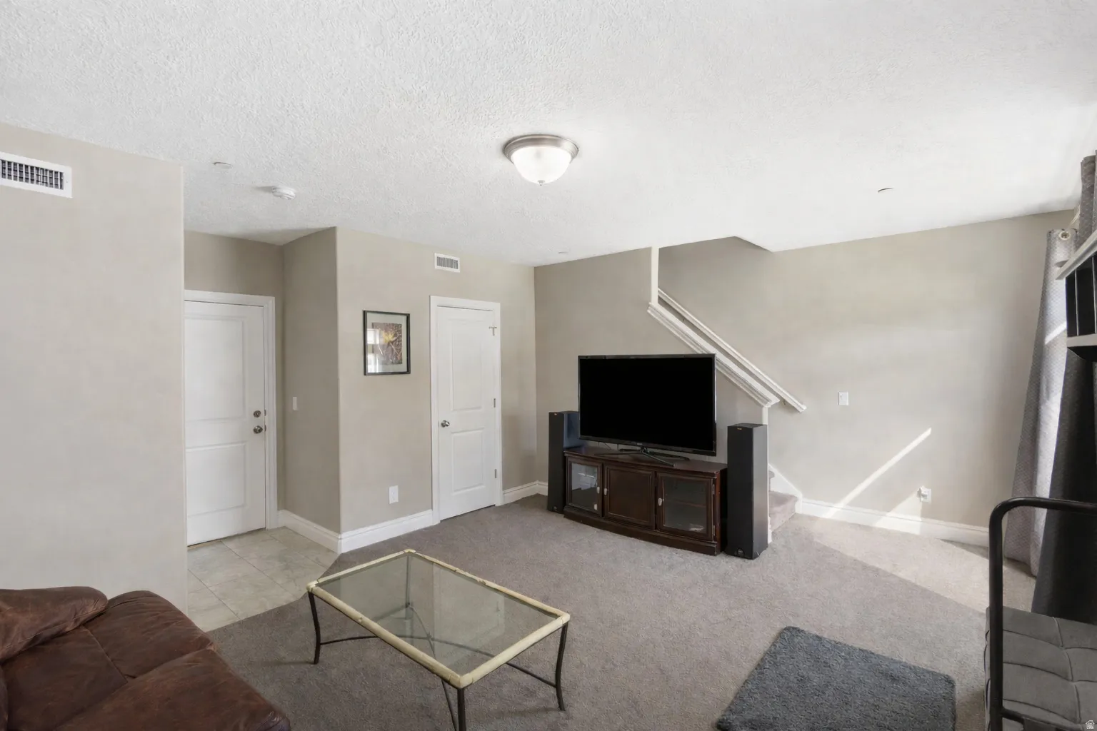 Living area with a textured ceiling and light colored carpet