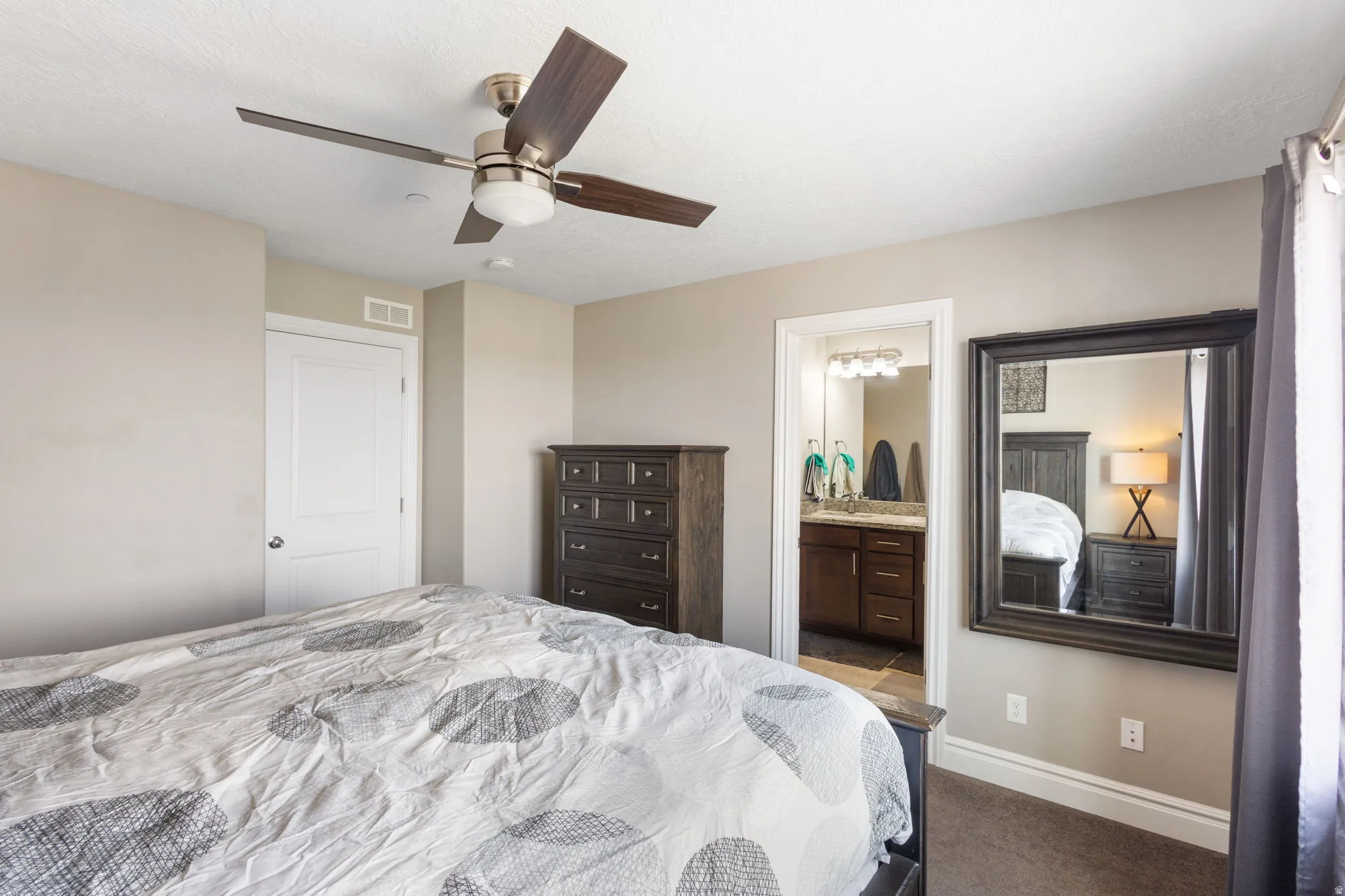 Carpeted bedroom featuring ceiling fan and connected bathroom
