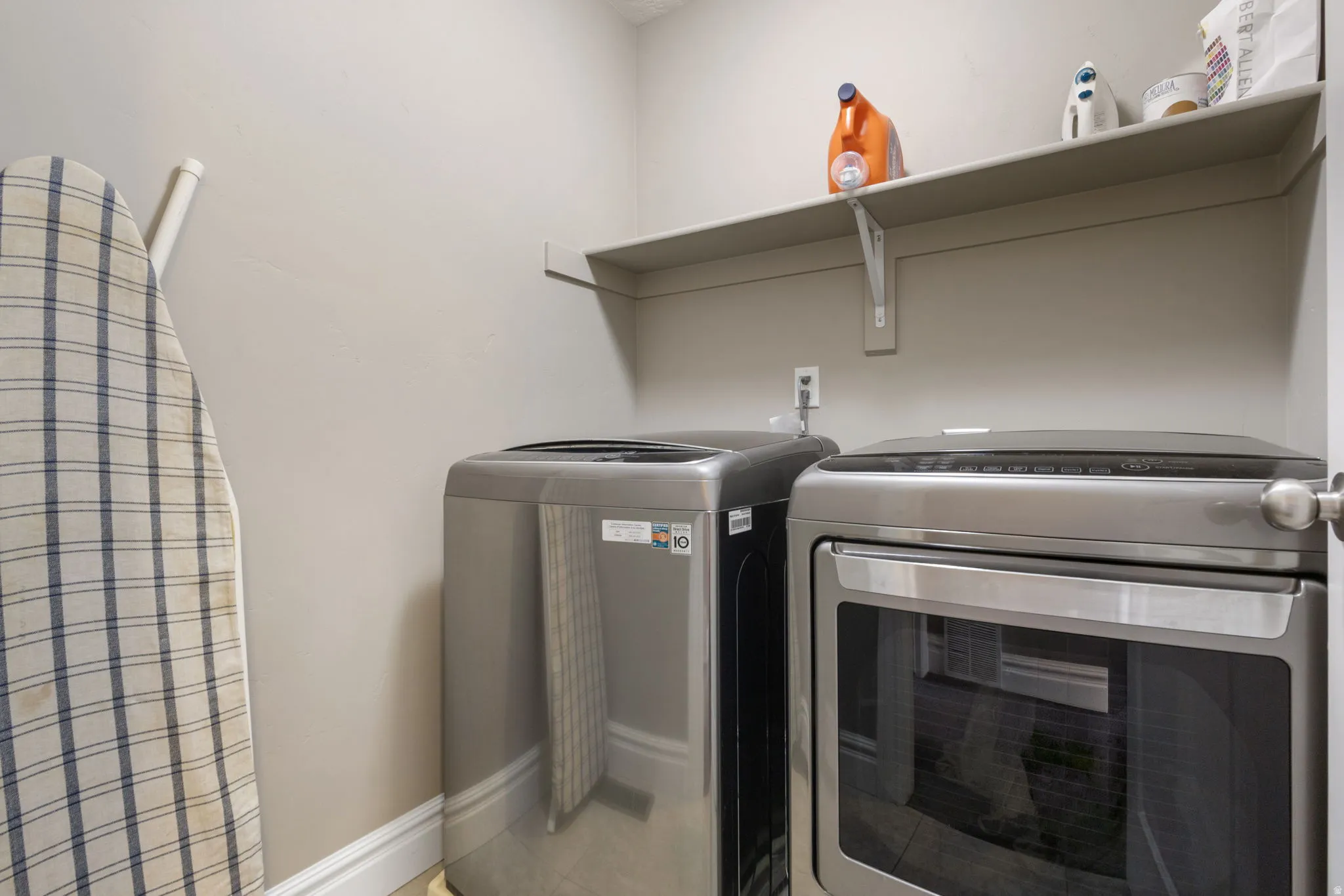 Laundry room with independent washer and dryer and light tile patterned flooring