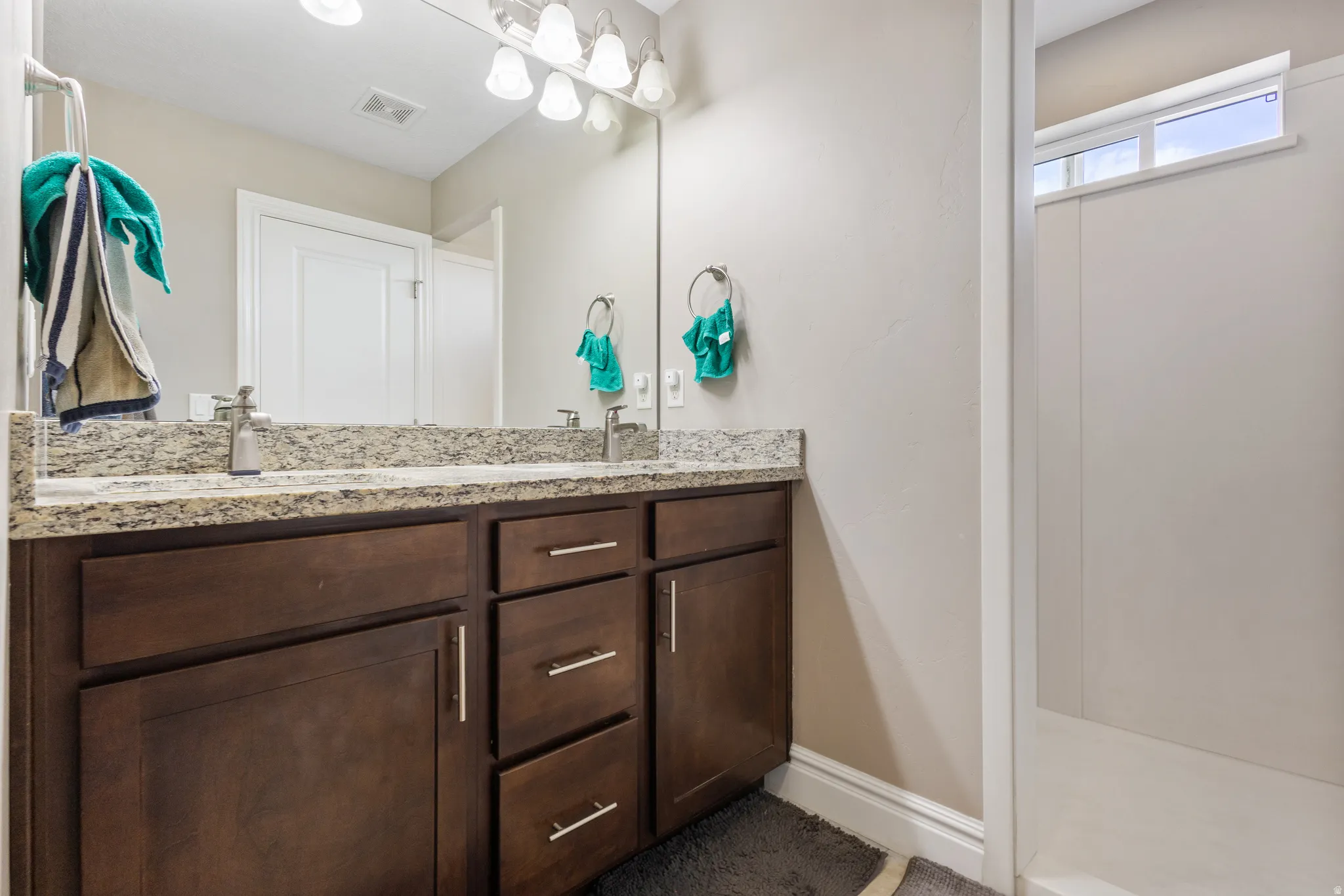Full bathroom featuring double vanity and baseboards