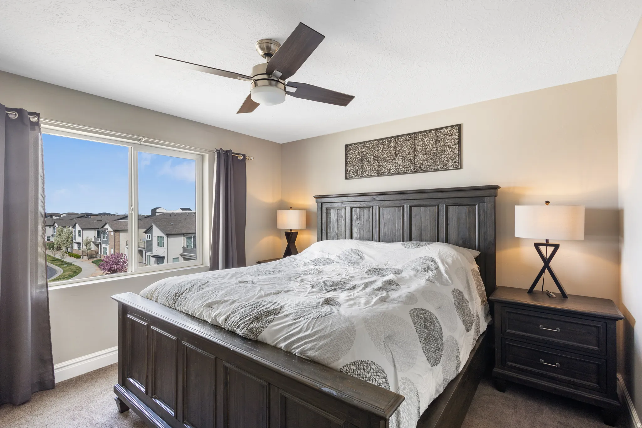 Bedroom with dark carpet, ceiling fan, and a residential view