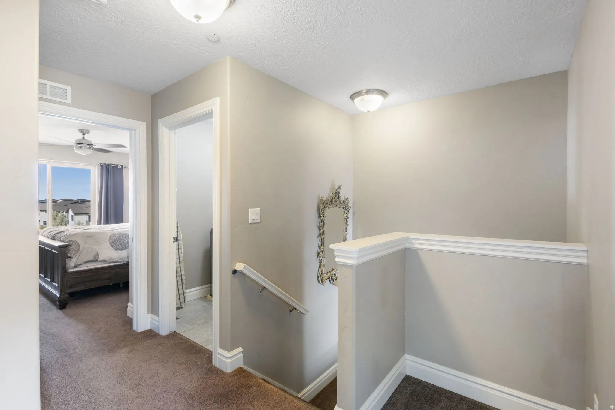Corridor with an upstairs landing, dark carpet, and a textured ceiling