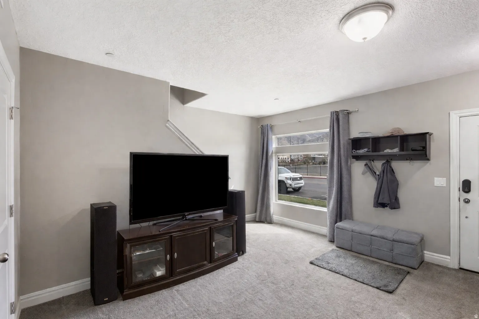 Living area with light carpet and a textured ceiling
