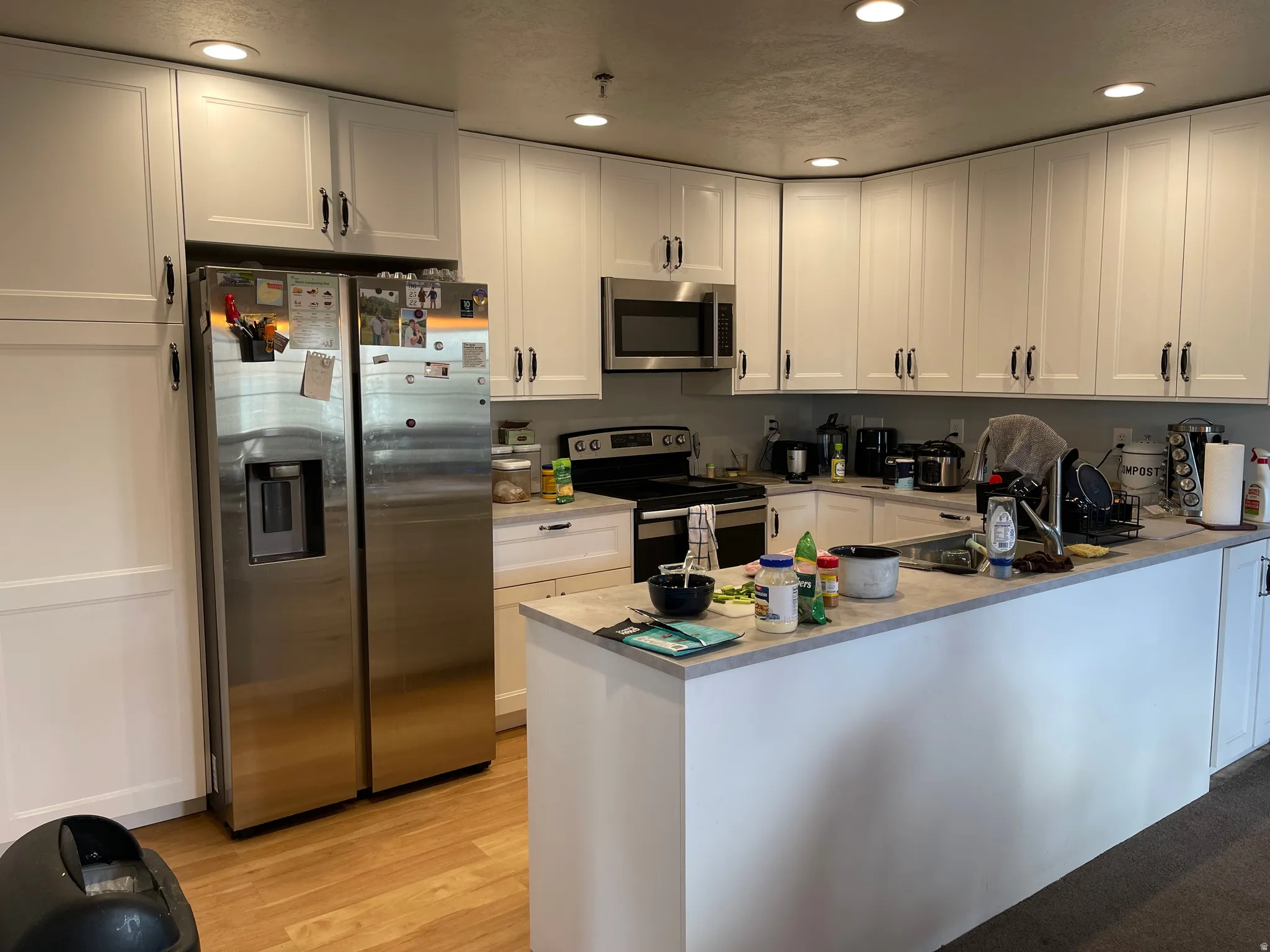Kitchen with stainless steel appliances, white cabinets, recessed lighting, light countertops, and LVP flooring
