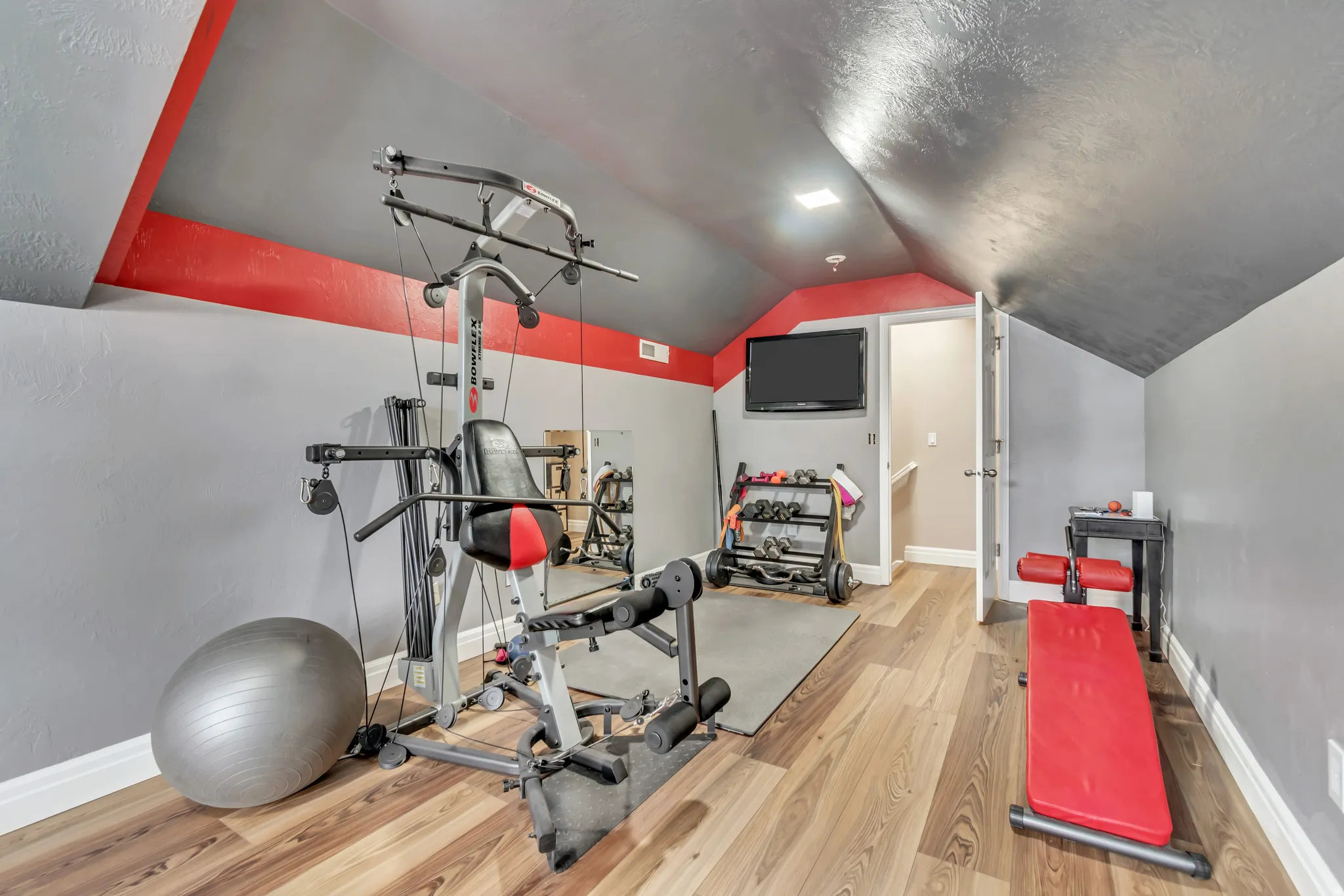 Second-floor bonus room that works perfectly for this exercise room with LVP floors and vaulted ceiling.