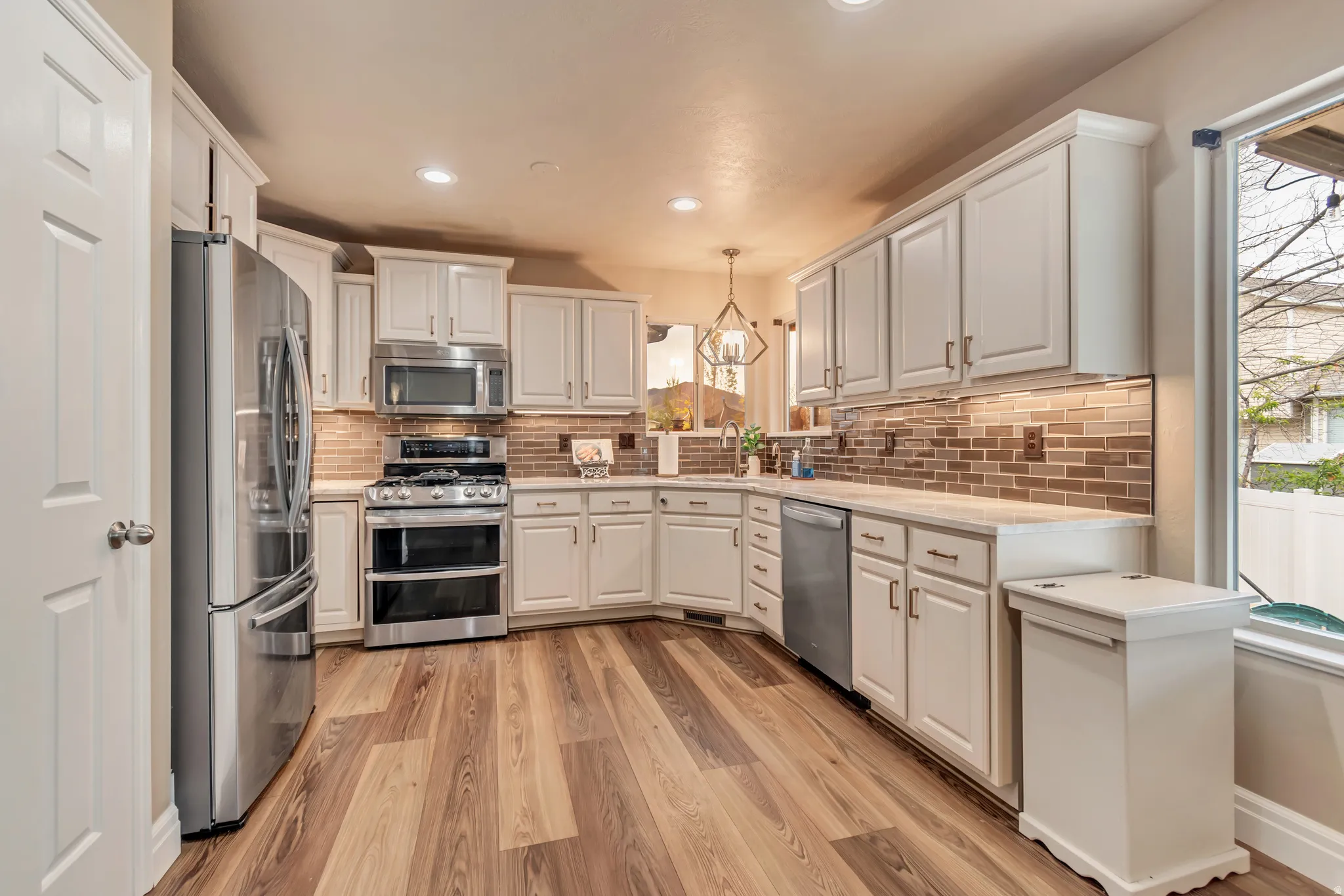 Impeccably upgraded kitchen, featuring stainless steel appliances, white cabinetry and light LVP floors.