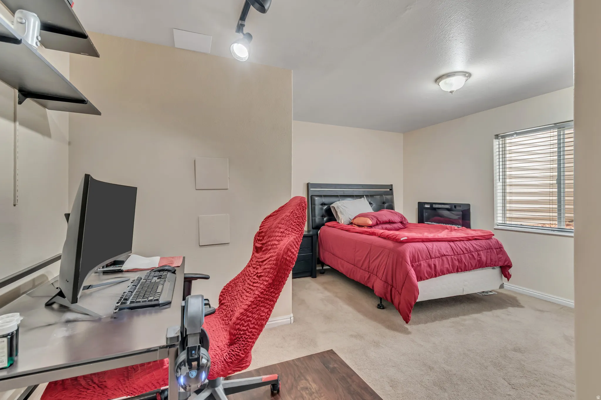 Basement bedroom featuring an office area, light carpet and rail lighting.