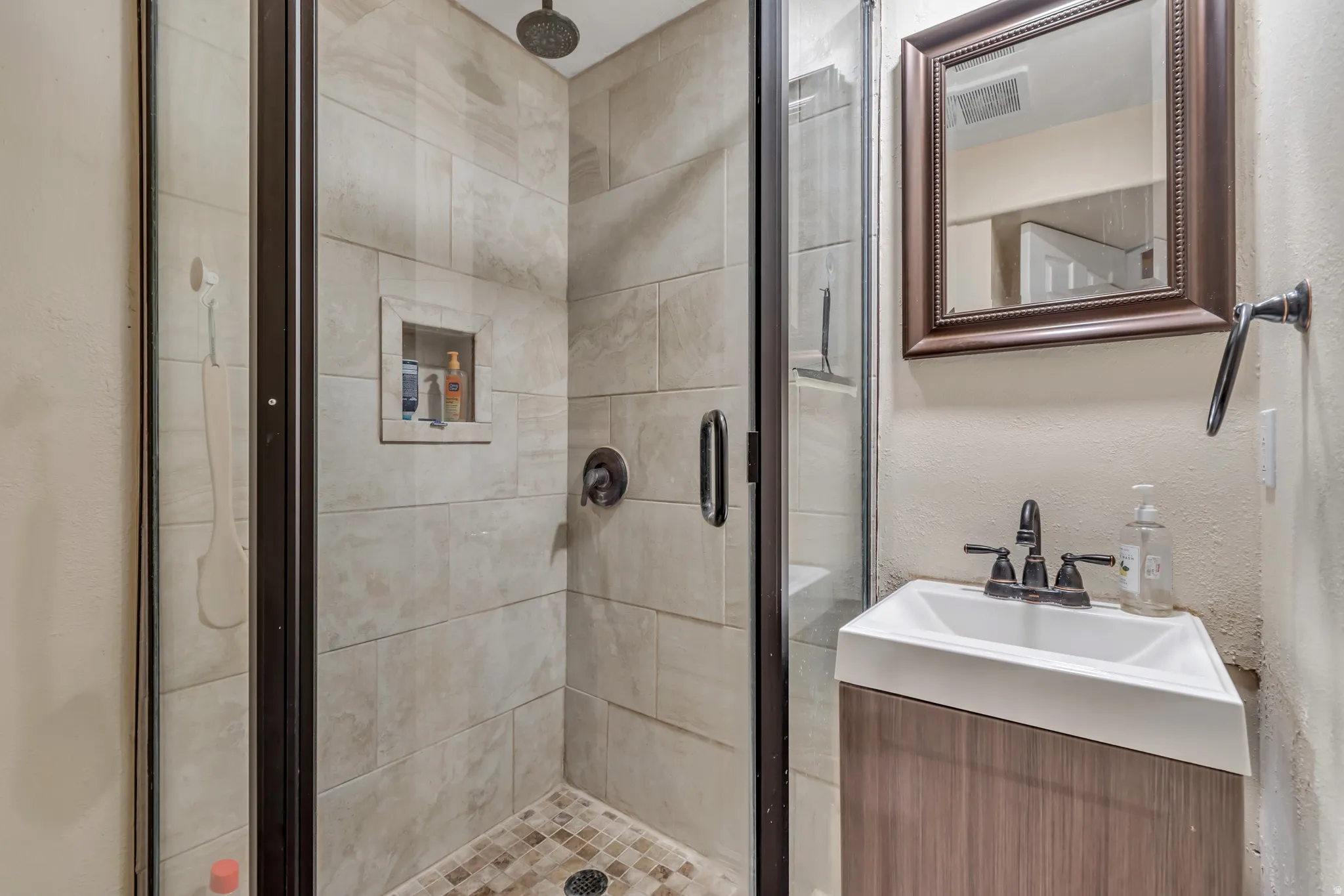 Updated downstairs bathroom featuring vanity and tiled shower stall.