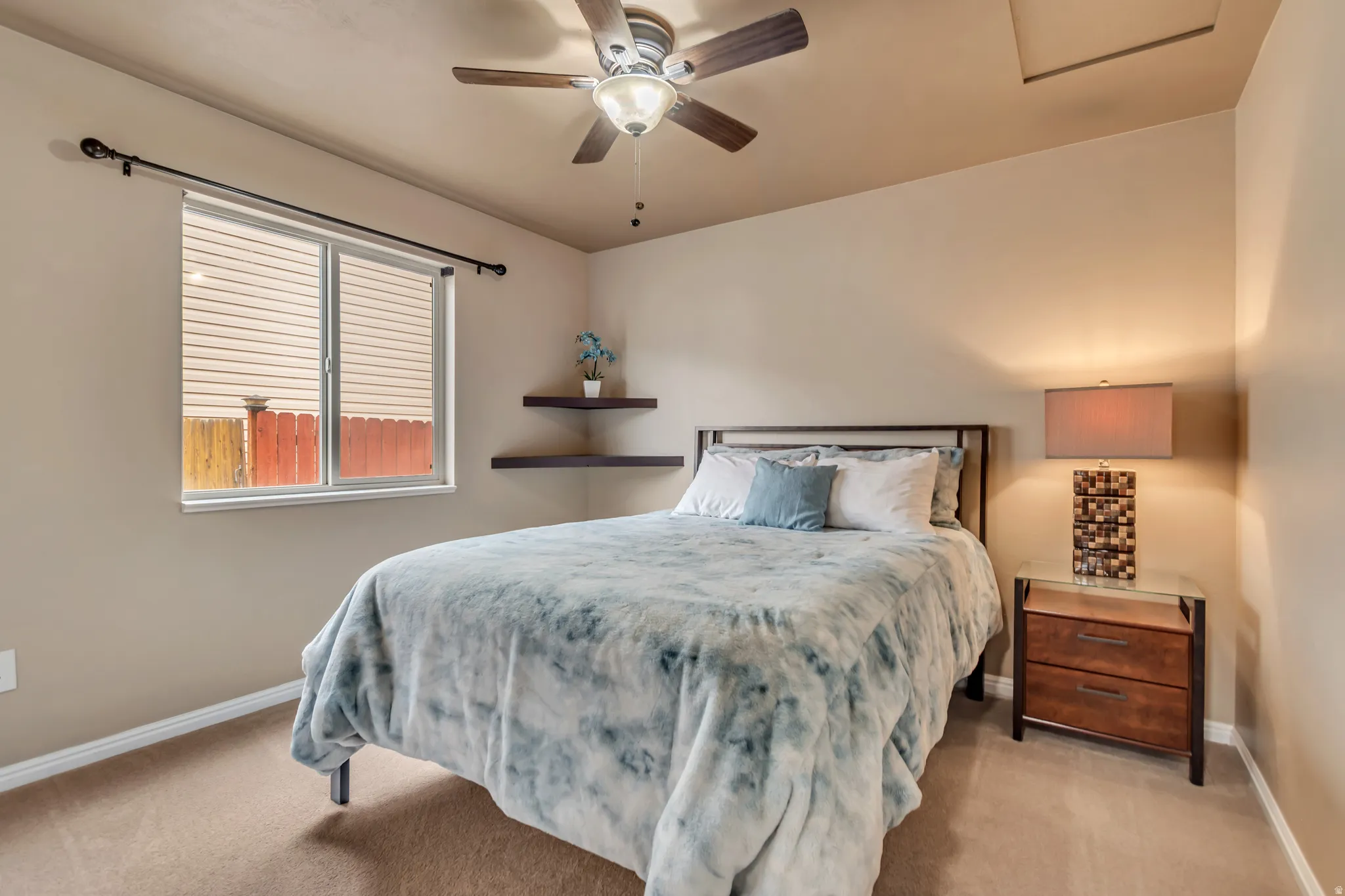 Bright and airy guest bedroom featuring a ceiling fan and light Karastan premium carpeting.