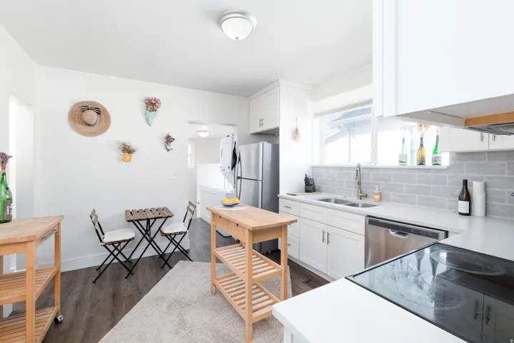 Kitchen with white cabinetry, backsplash, dark wood-type flooring, stainless steel appliances, and light quartz countertops