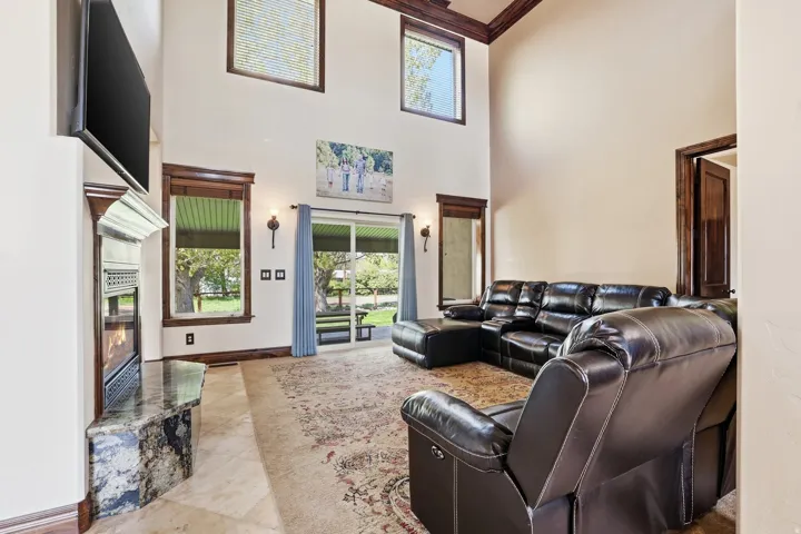 Living area featuring high vaulted ceilings with wood trim accents and a fireplace with a stone hearth