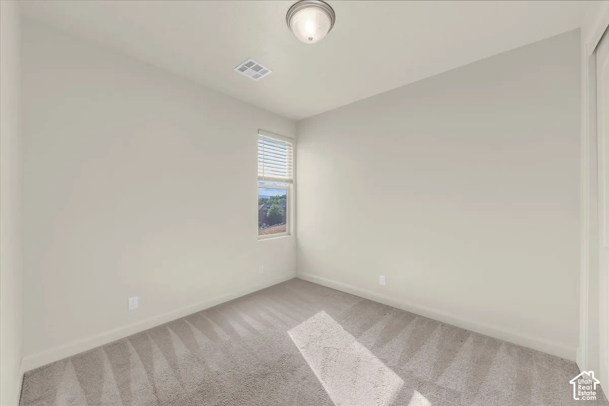 Spare room with baseboards and light carpet