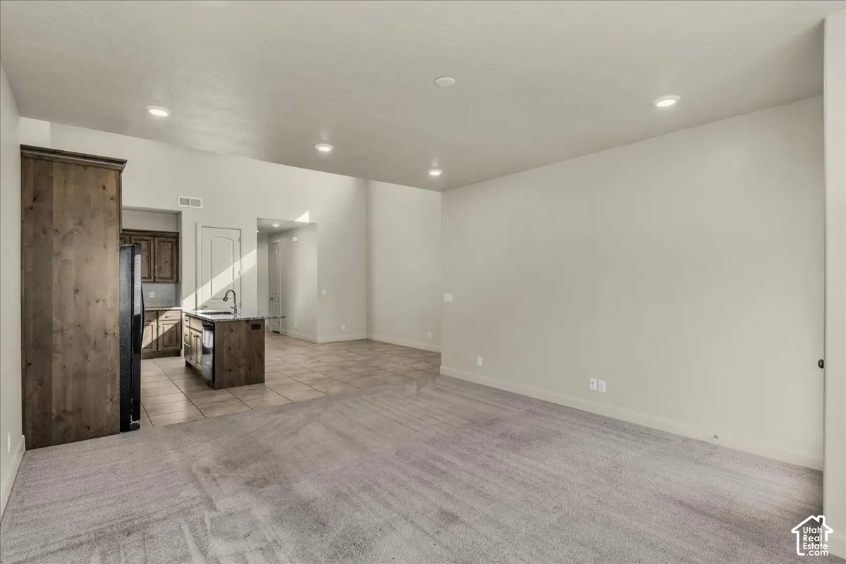 Unfurnished living room featuring light carpet, light tile patterned flooring, and recessed lighting
