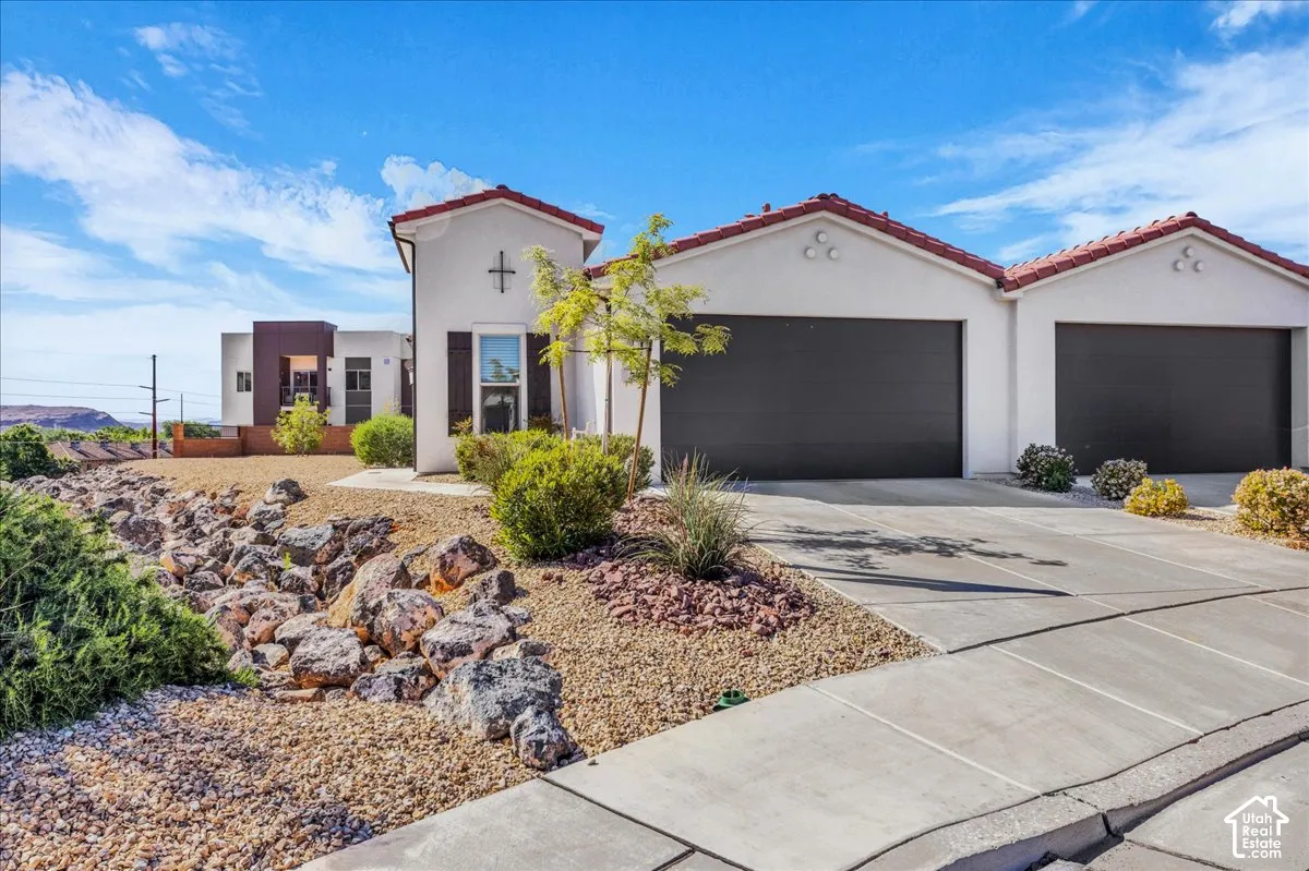 Mediterranean / spanish-style house with driveway, stucco siding, an attached garage, and a tiled roof