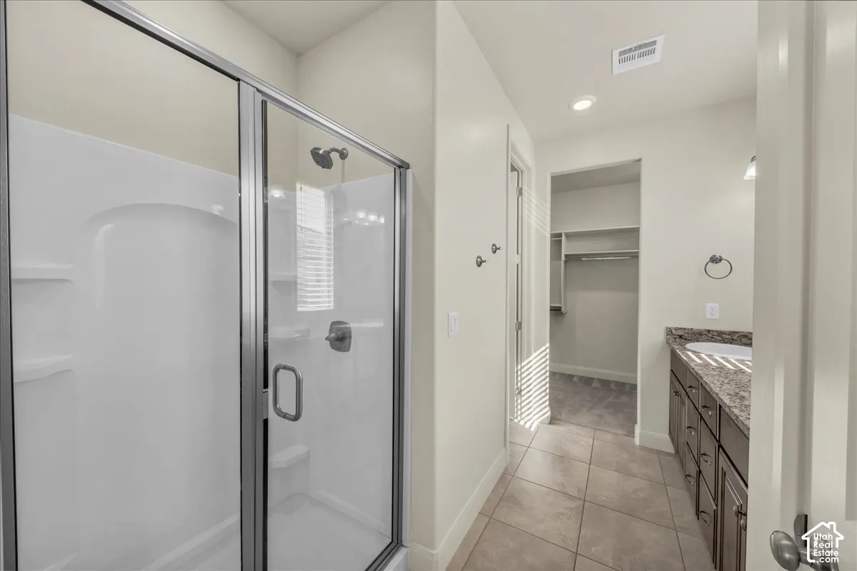 Full bath with vanity, a walk in closet, a shower stall, light tile patterned flooring, and recessed lighting