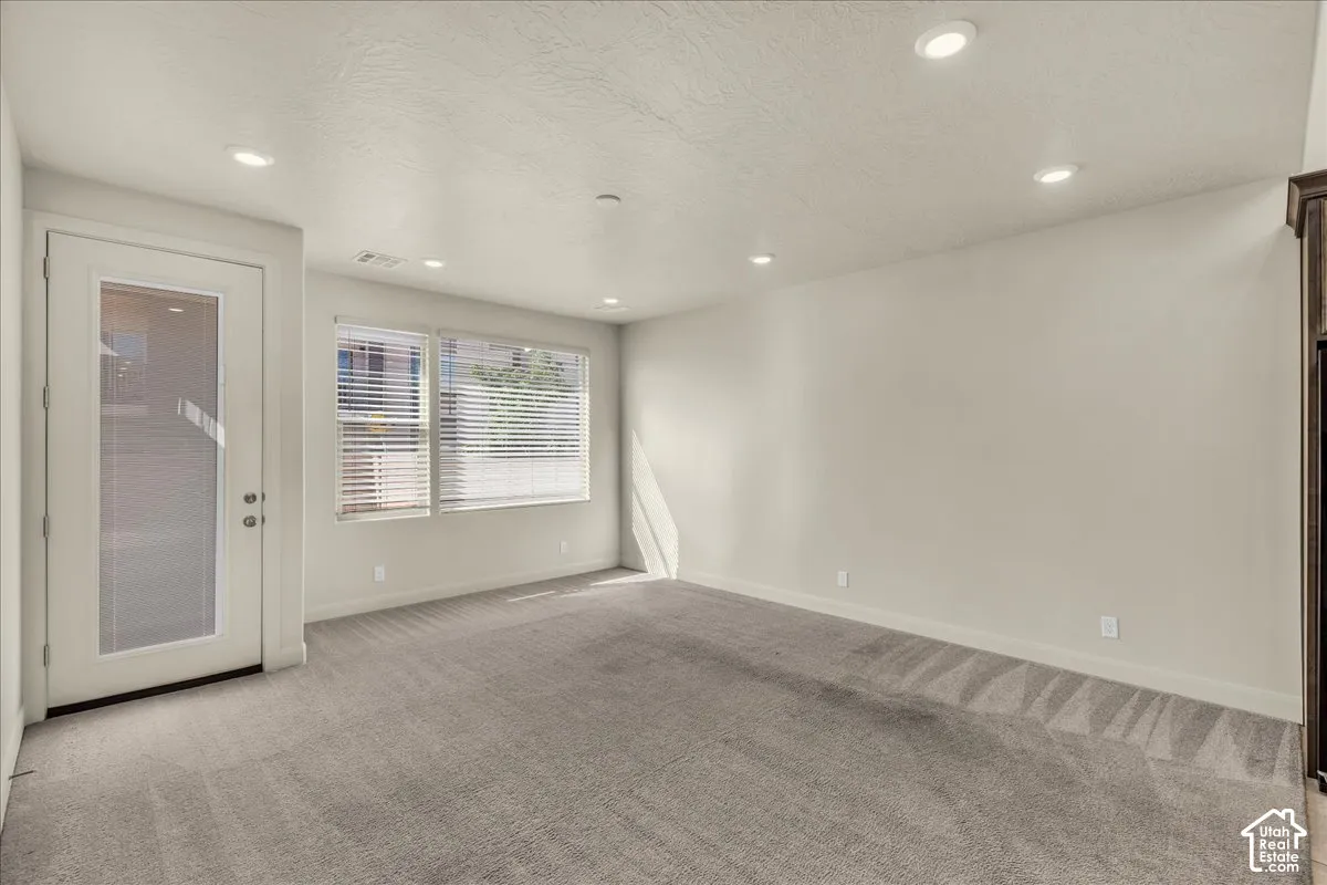Spare room featuring light carpet, a textured ceiling, and recessed lighting