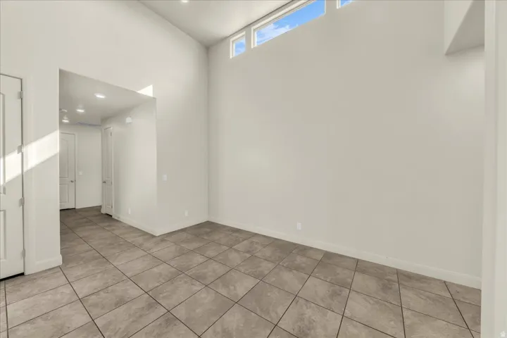Empty room with a high ceiling, recessed lighting, and light tile patterned flooring