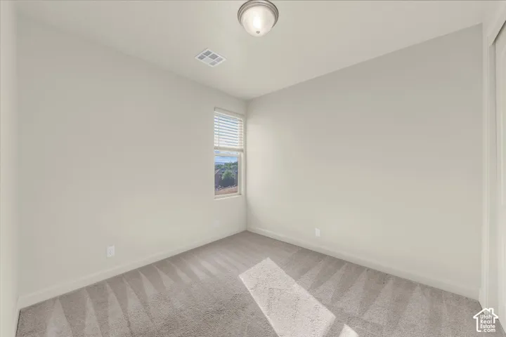 Spare room with baseboards and light carpet