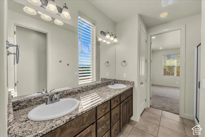 Bathroom with double vanity, light tile patterned floors, light carpet, and recessed lighting