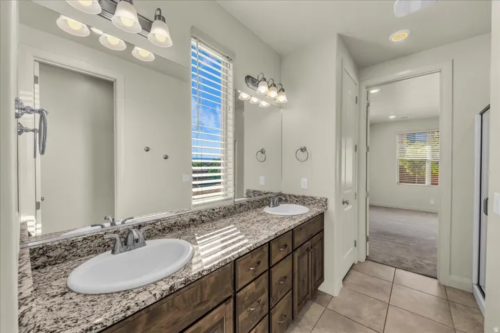 Bathroom with double vanity, light tile patterned floors, light carpet, and recessed lighting