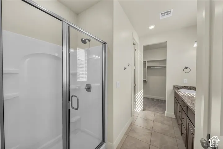 Full bath with vanity, a walk in closet, a shower stall, light tile patterned flooring, and recessed lighting