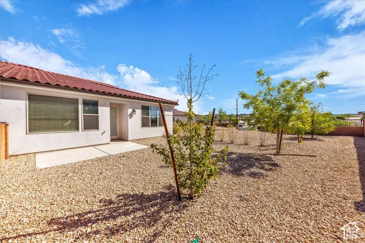Back of house featuring a patio area, stucco siding, a fenced backyard, and a tile roof