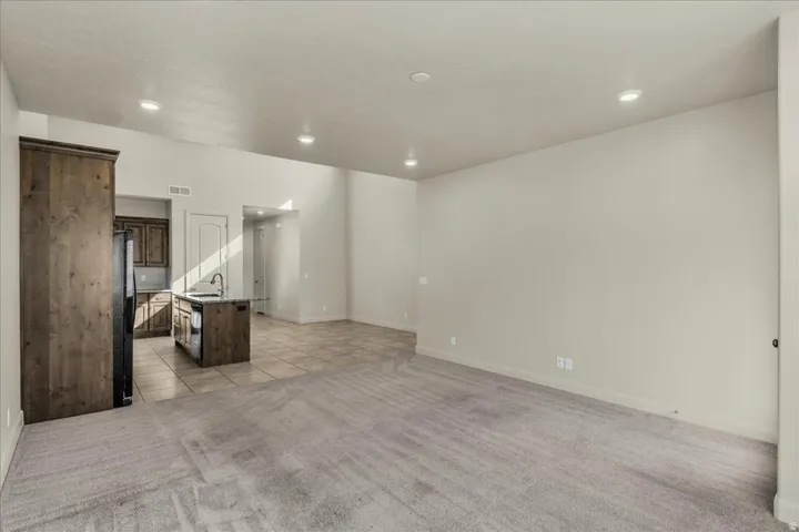 Unfurnished living room featuring light carpet, light tile patterned flooring, and recessed lighting