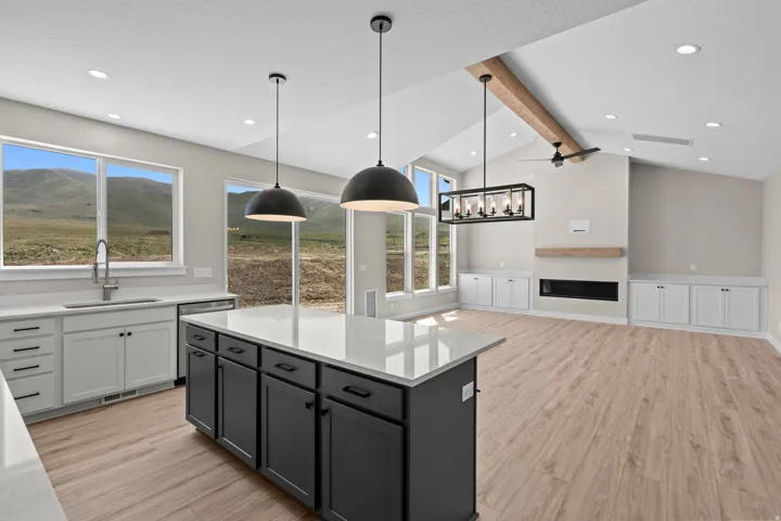 Kitchen featuring two tone cabinets, light wood-style floors, a kitchen island, light stone counters, and decorative light fixtures