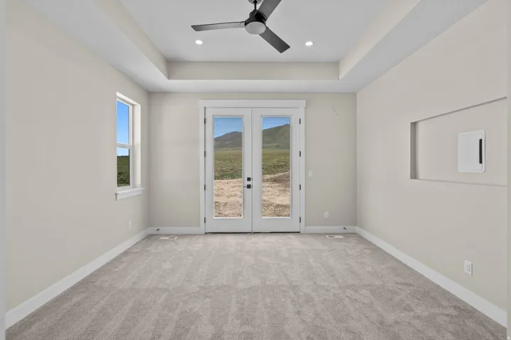 Unfurnished room with french doors, a tray ceiling, light carpet, a ceiling fan, and recessed lighting