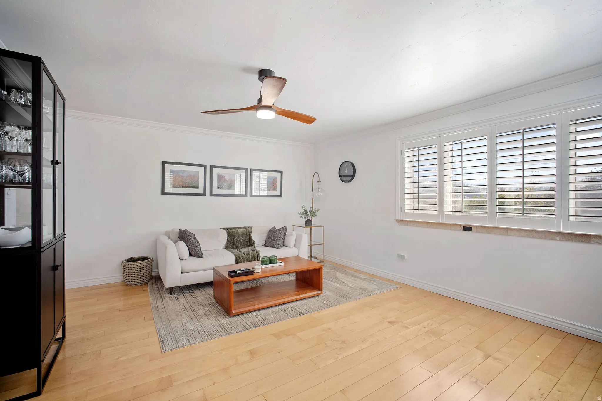 Living room featuring light wood finished floors, ornamental molding, and a ceiling fan