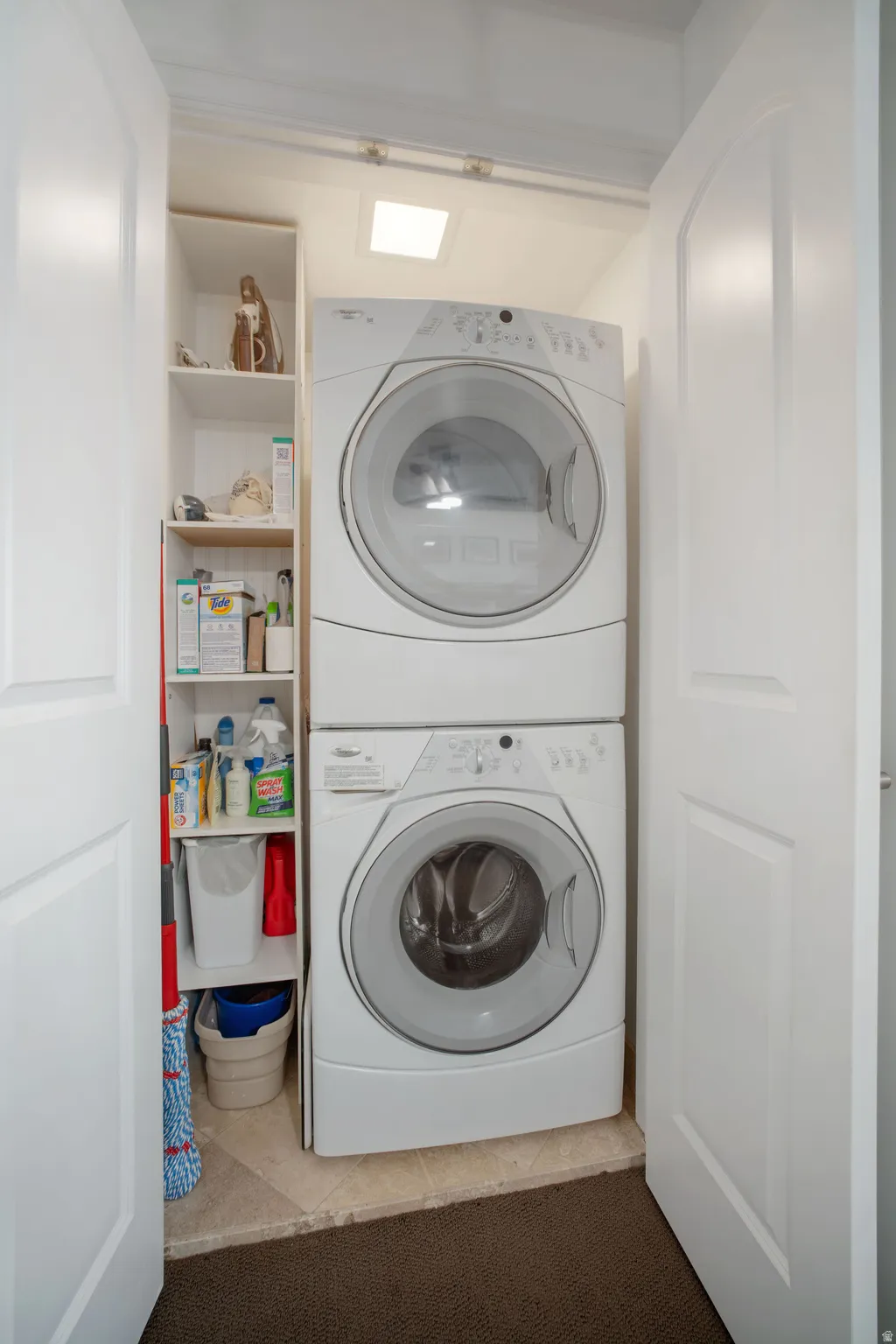 Laundry area featuring stacked washer / drying machine and light tile patterned floors
