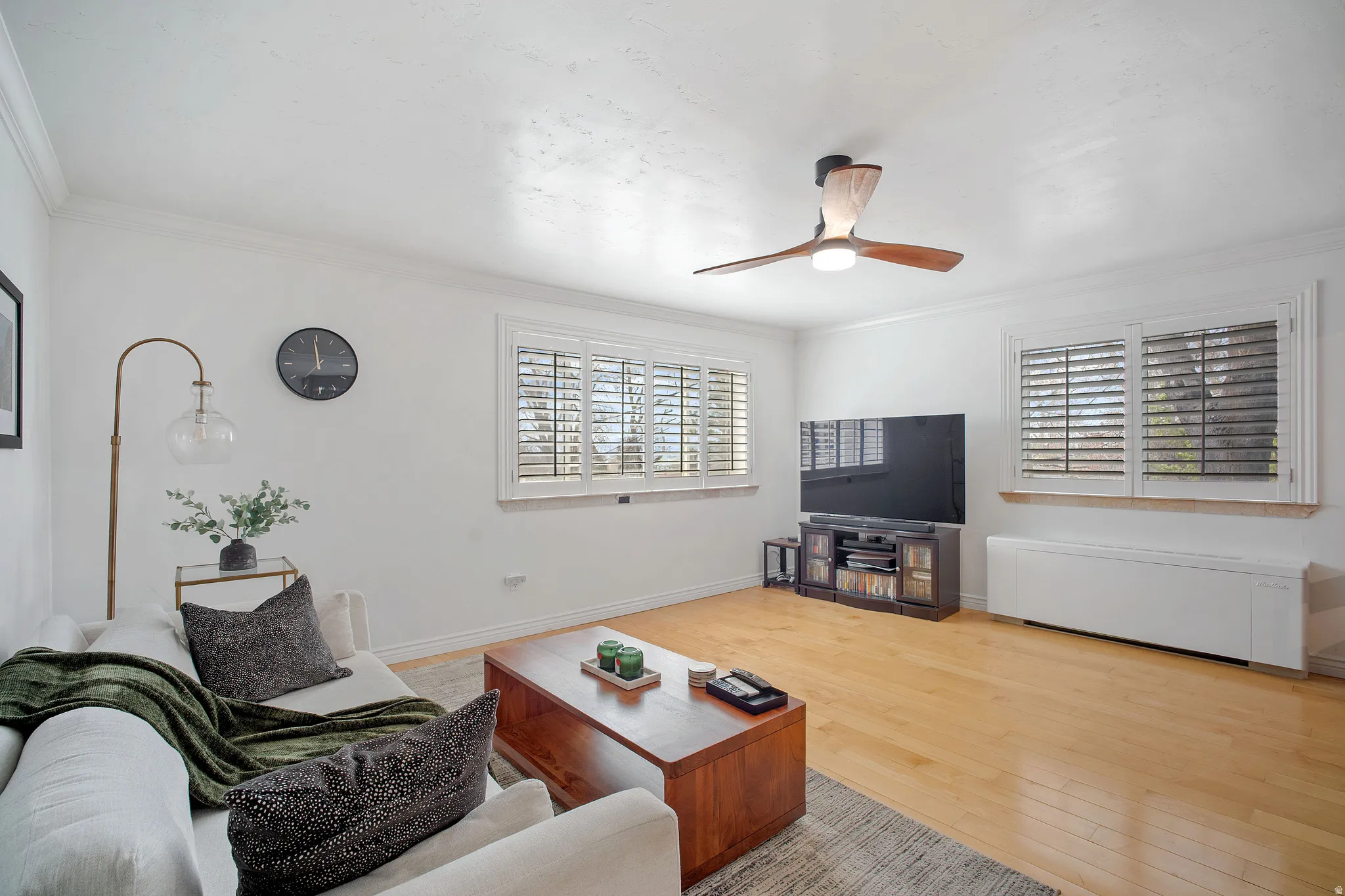 Living room with wood-type flooring, crown molding, and a ceiling fan