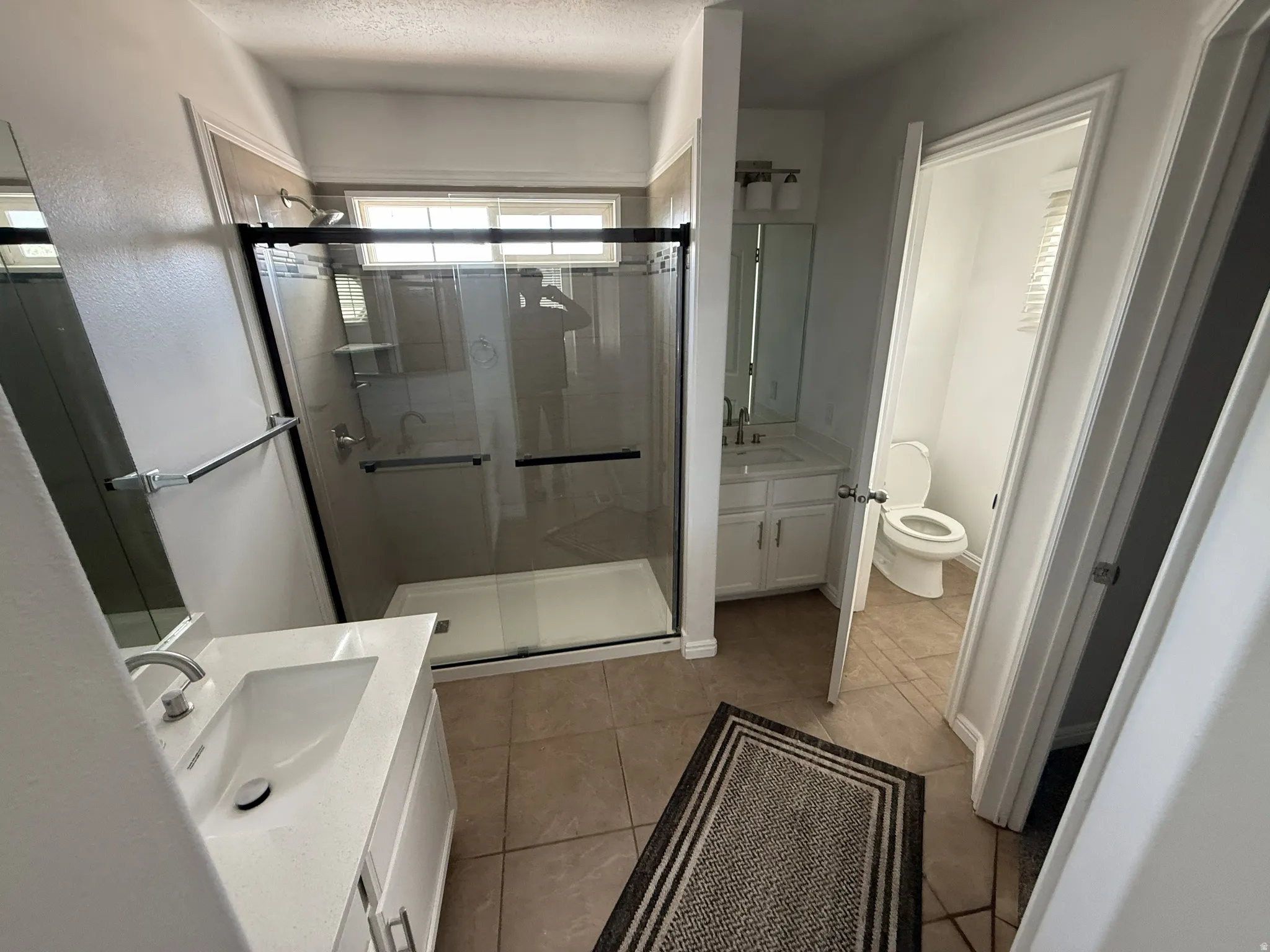 Bathroom with vanity, a shower stall, and light tile patterned floors
