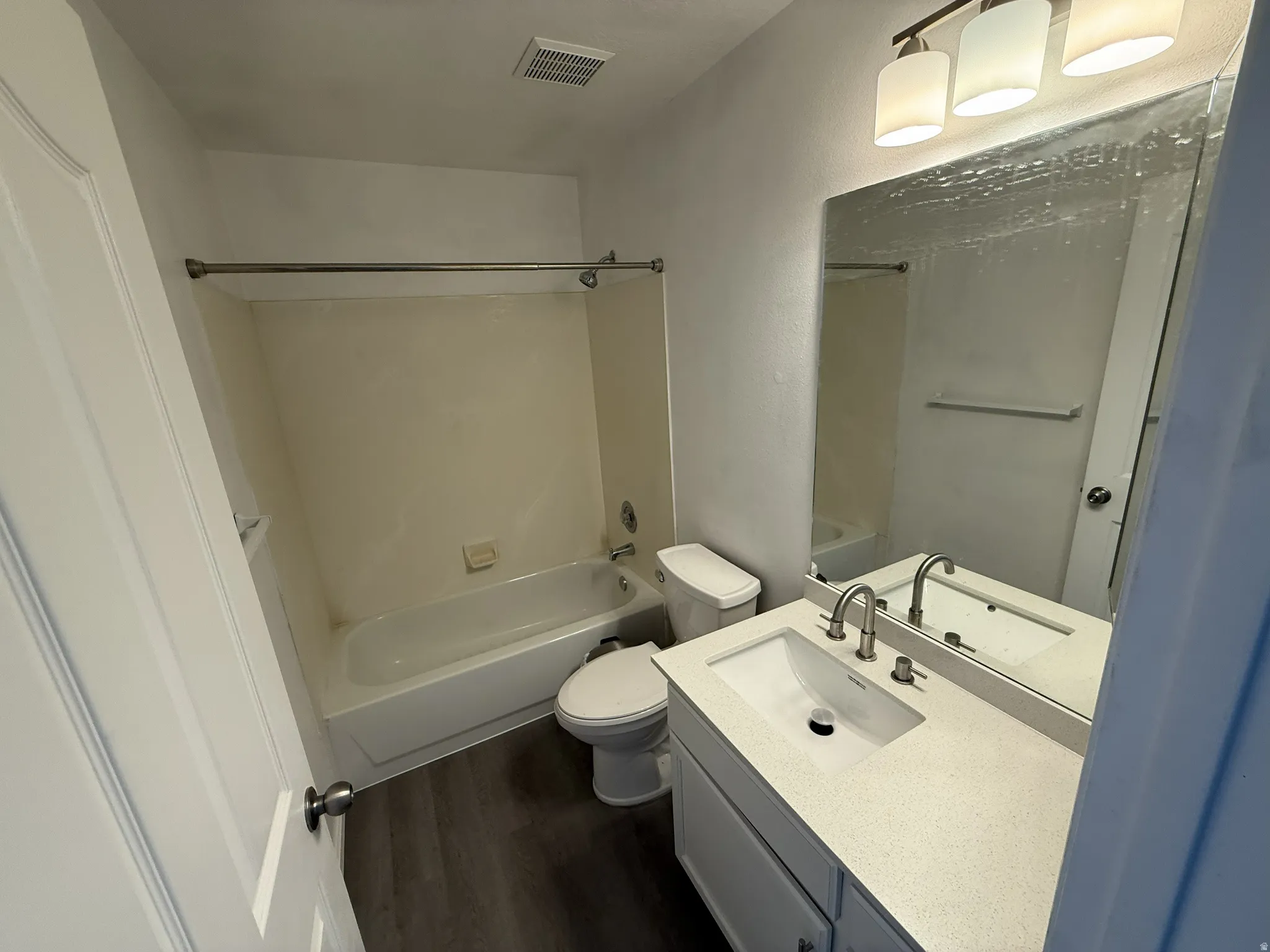 Bathroom with vanity, tub / shower combination, and dark wood-type flooring