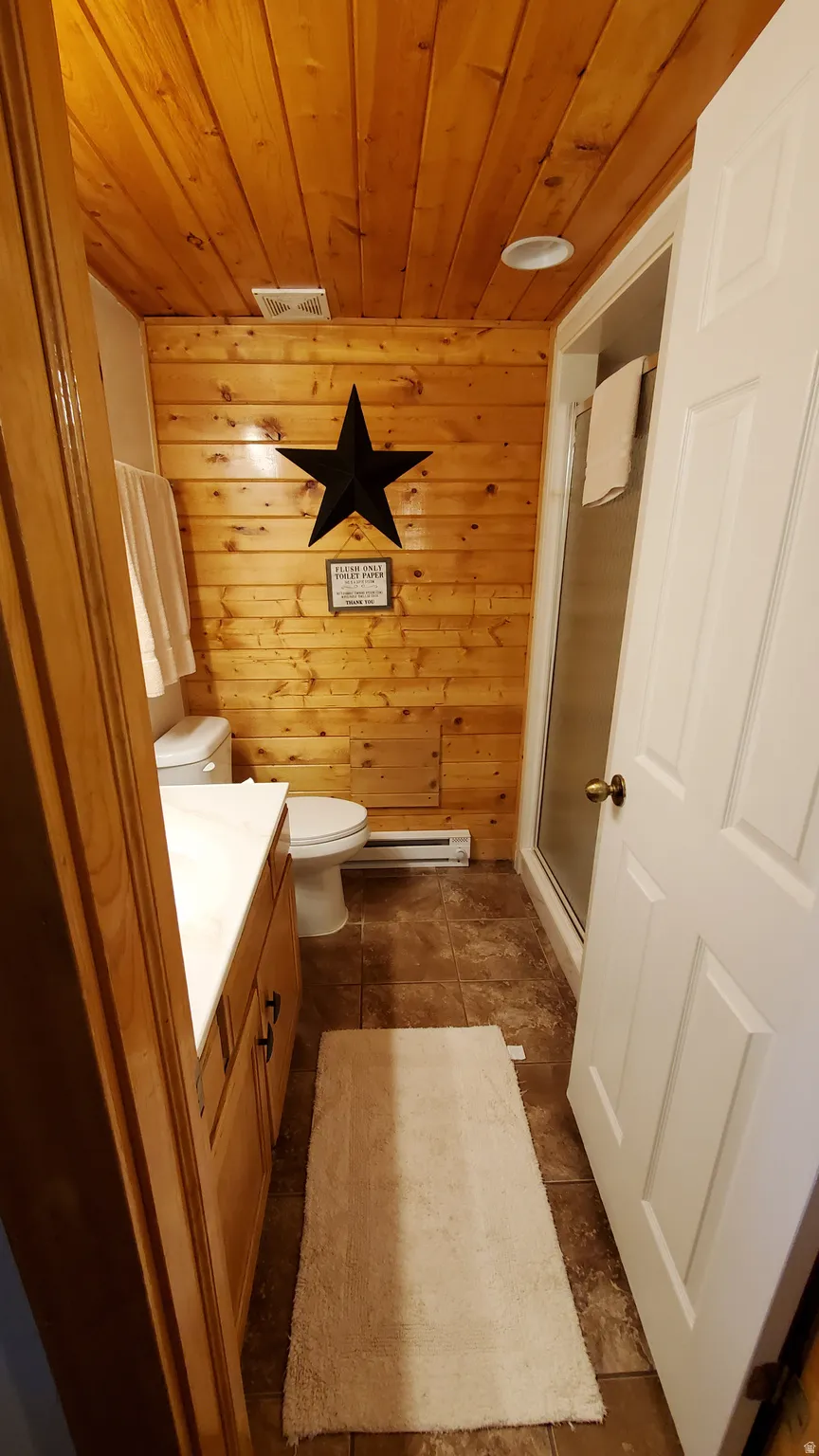 Bathroom with wooden walls, vanity, a stall shower, wood ceiling, and dark tile patterned flooring