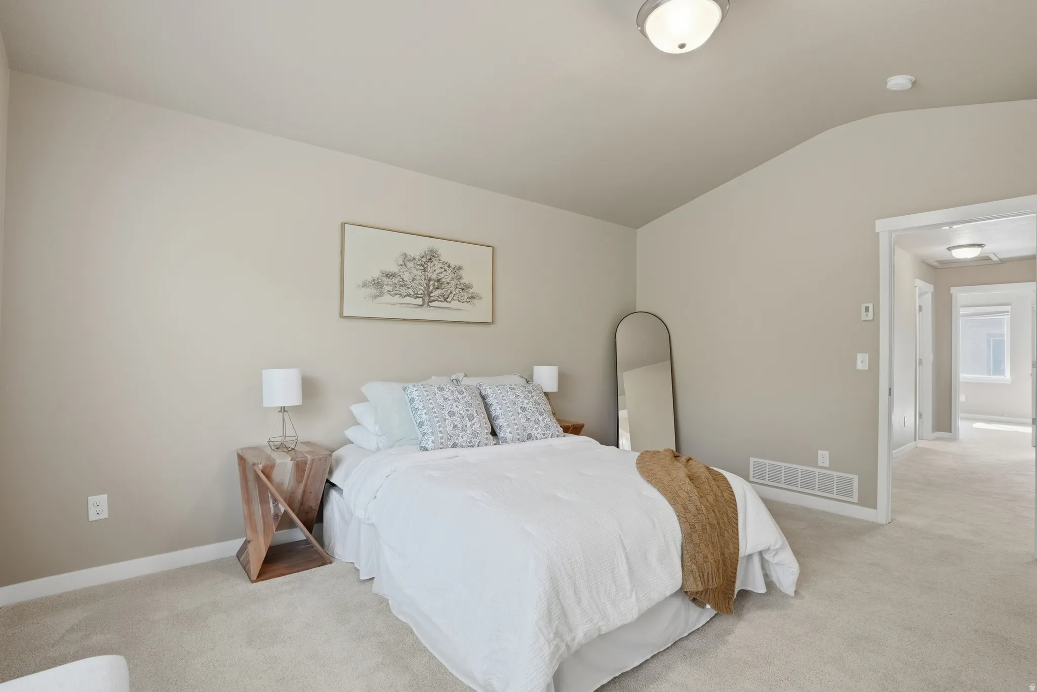 Bedroom with light carpet and vaulted ceiling